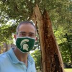 Chris Long in green and white Spartan mask in front of the Resilient Tree