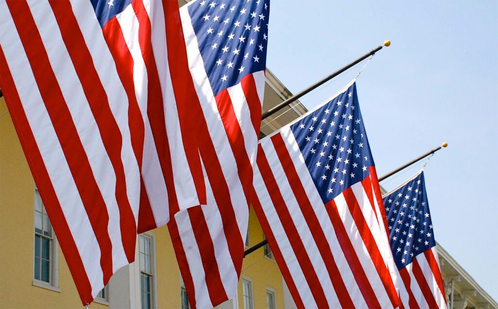 American Flags lined up against a yellow building