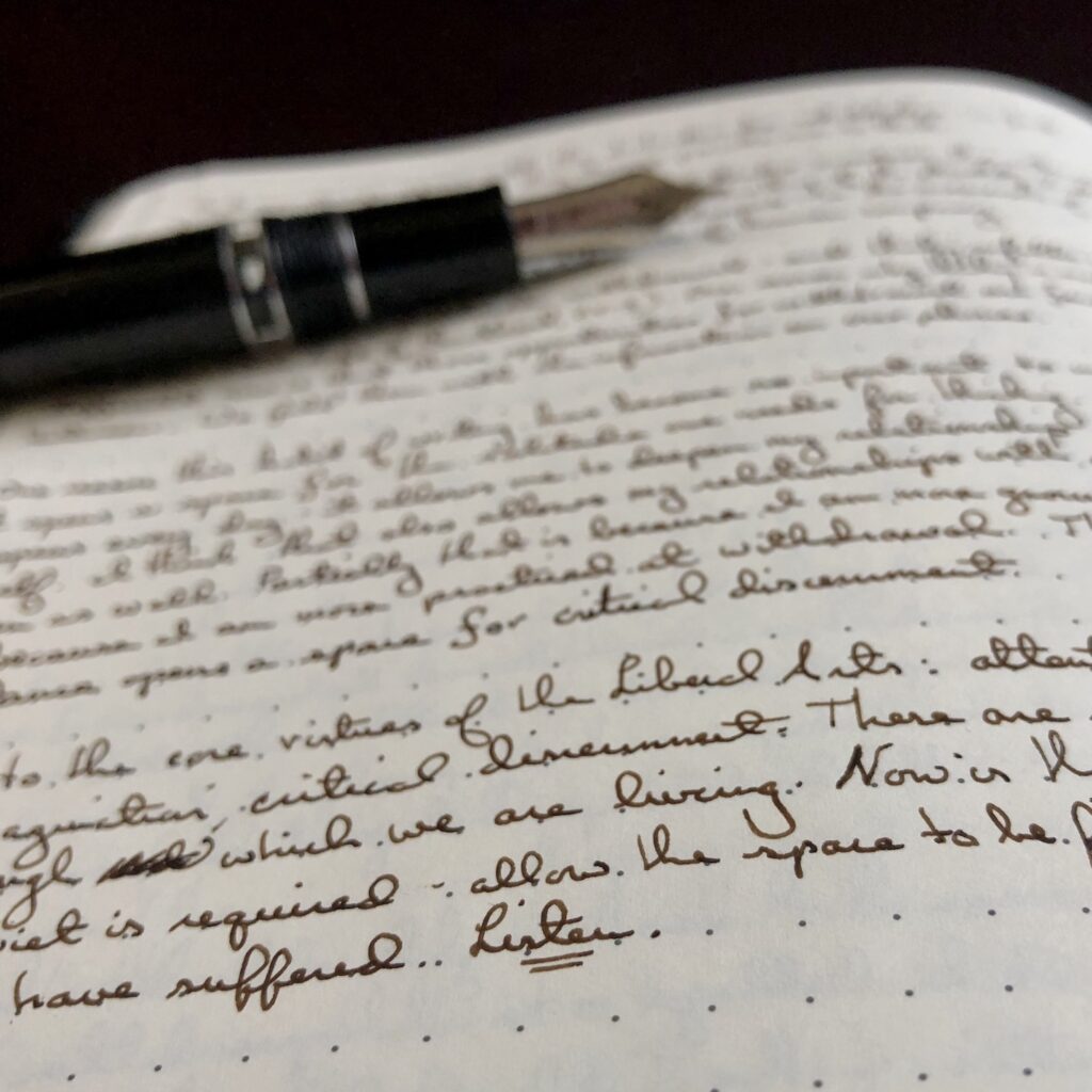 A page from Christopher P. Long's journal, illustrating his daily writing practice. Brown ink on dot grid paper, with a Sailor Realo pen out of focus on lying on the page. The word "Listen" is underlined and legible in his small cursive handwriting. Much of the text on the page is not legible.